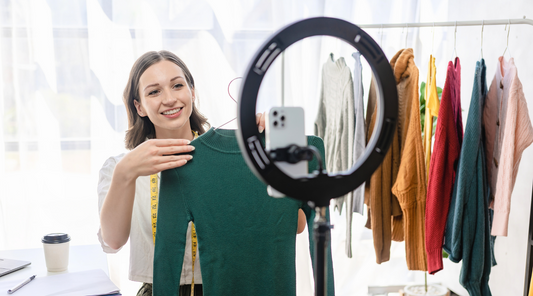 Influencerin präsentiert Kleidung vor Smartphone und Ringlicht – Mode, Livestream, Online-Shopping.