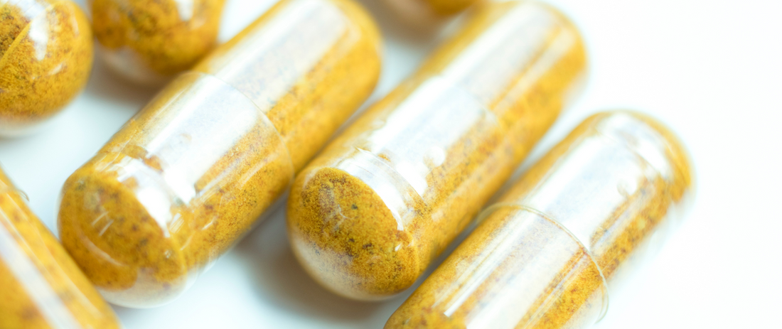 Mehrere Medikamentenkapseln auf einem weißen Hintergrund zu sehen, die gelb sind. 