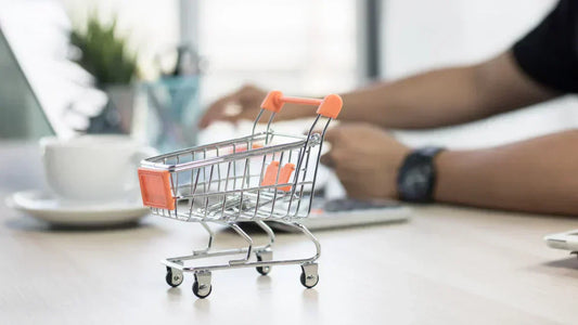 Dark Patterns im Online-Shop: Kleiner Einkaufswagen auf Schreibtisch für Design-Audit.