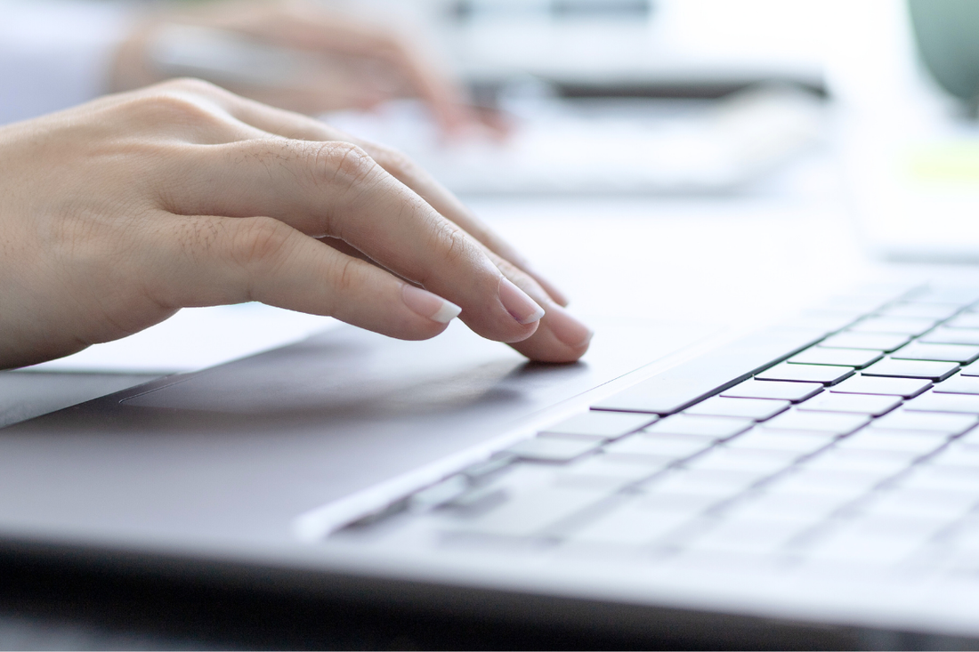 Hand nutzt ein Laptop-Touchpad im hellen Büro – konzentriertes Arbeiten und digitale Produktivität im Arbeitsalltag.