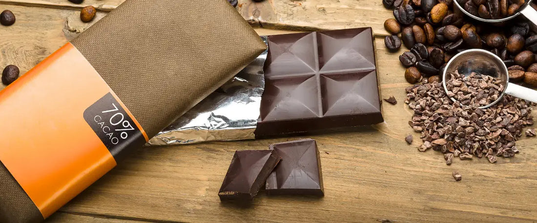 LMIV-Kennzeichnungspflicht Beispiel: 70% Schokolade mit Verpackung neben Kaffeebohnen auf Holz.