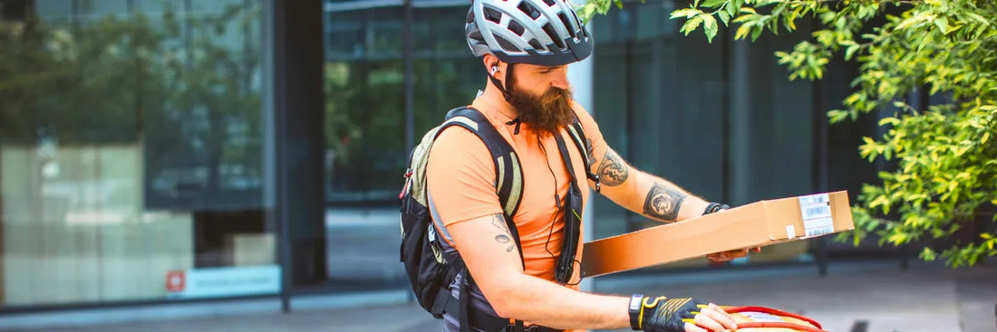 Mann mit Fahrrad bringt Paket zur Post – Rücksendekosten bei Retoure und Widerruf im Online-Handel