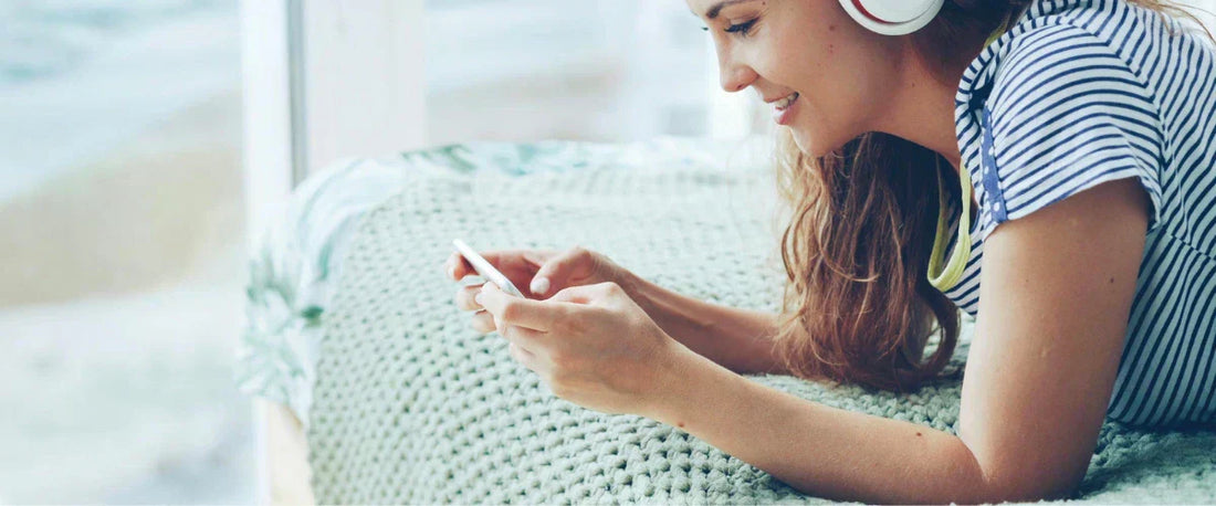 Musikrechte für Social Media: Frau mit Kopfhörern erstellt rechtssichere Reels am Handy.