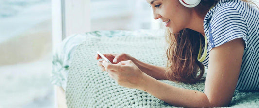 Musikrechte für Social Media: Frau mit Kopfhörern erstellt rechtssichere Reels am Handy.