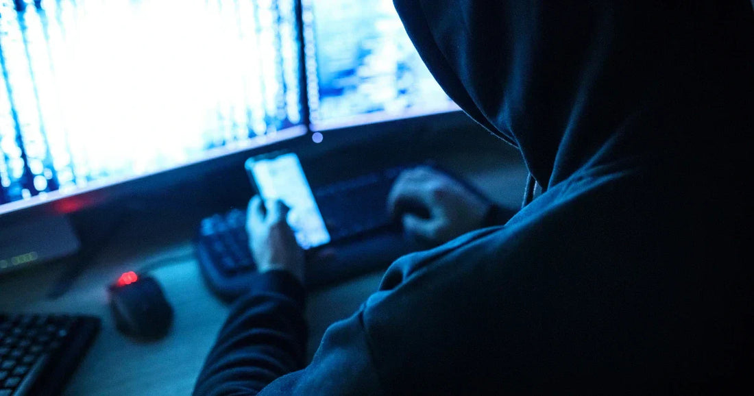 Notfallplan bei Datenpannen für Shops: Hacker mit Kapuze arbeitet an Monitoren.