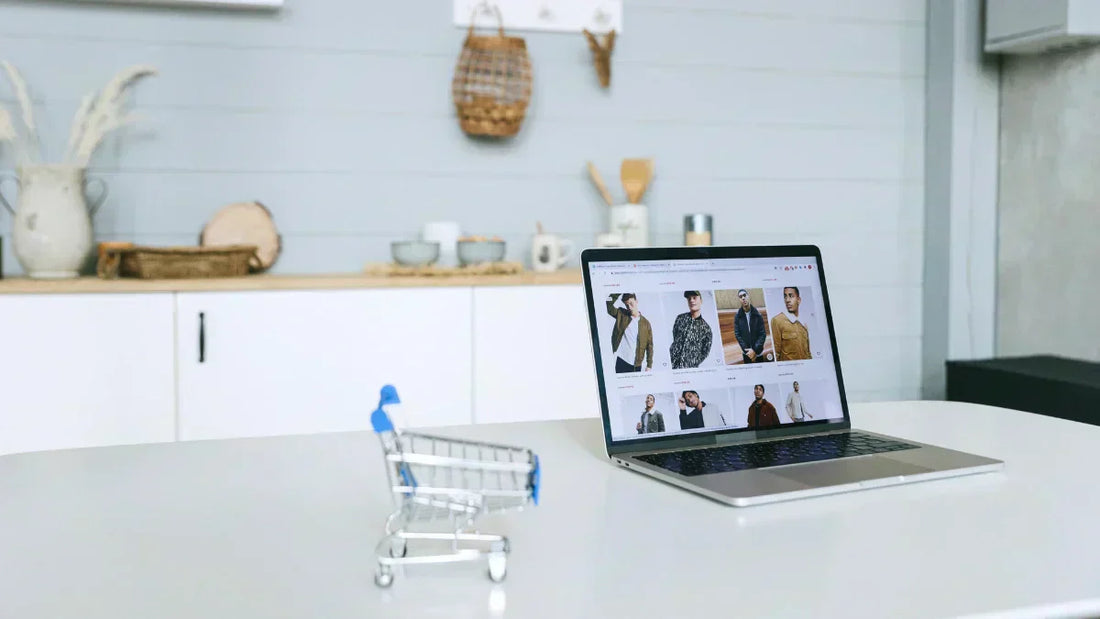 Produkthaftung bei Online-Einkauf: Laptop und kleiner Einkaufswagen auf einem weißen Tisch.