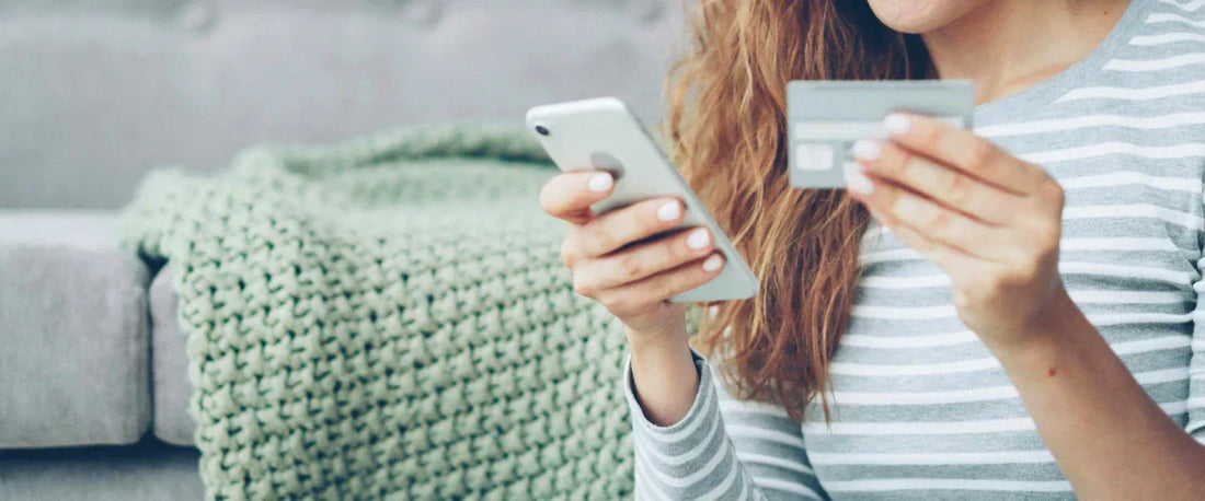Vertragsschluss im Online-Checkout: Eine Kundin nutzt Smartphone und Kreditkarte für den Kauf in einem Online-Shop.