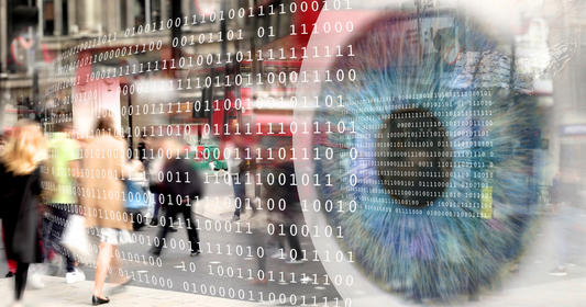 Ein großes Auge rechts, blau-grüne Iris, daneben Binärcode über dem Bild. Links unscharfe Passanten. Das Bild vermittelt den Eindruck von Beobachtung und digitaler Überwachung.
