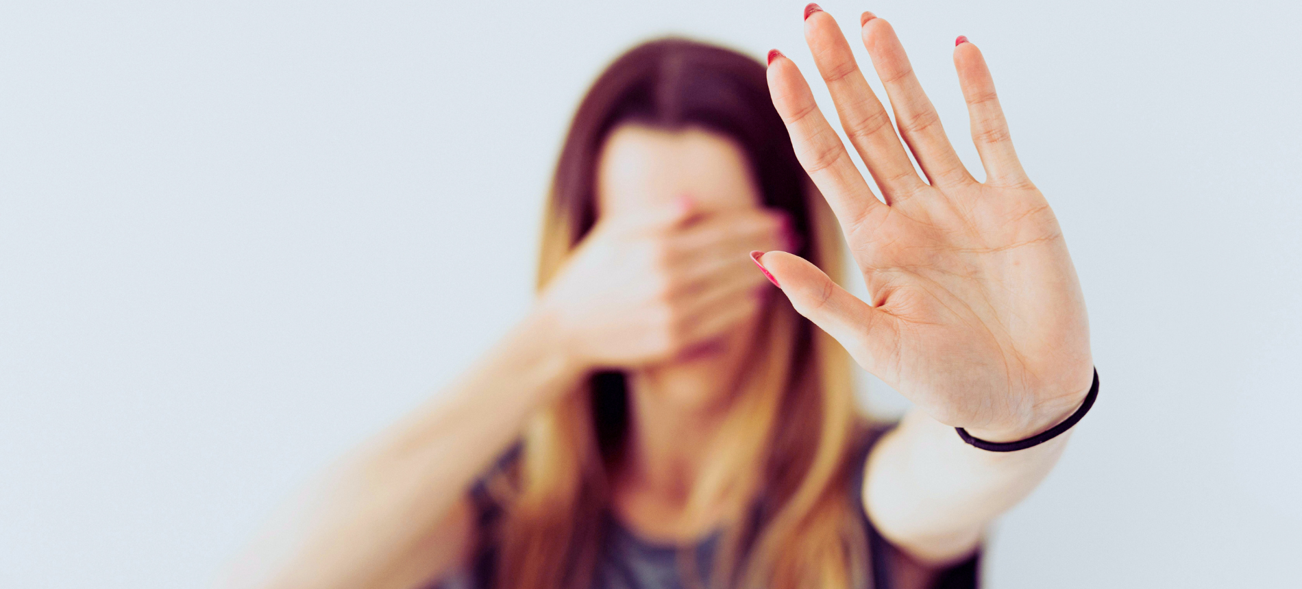 Frau hält warnend die Hand hoch und schützt ihr Gesicht – Symbol für Vorsicht vor Online-Betrug und Fake-Shops.