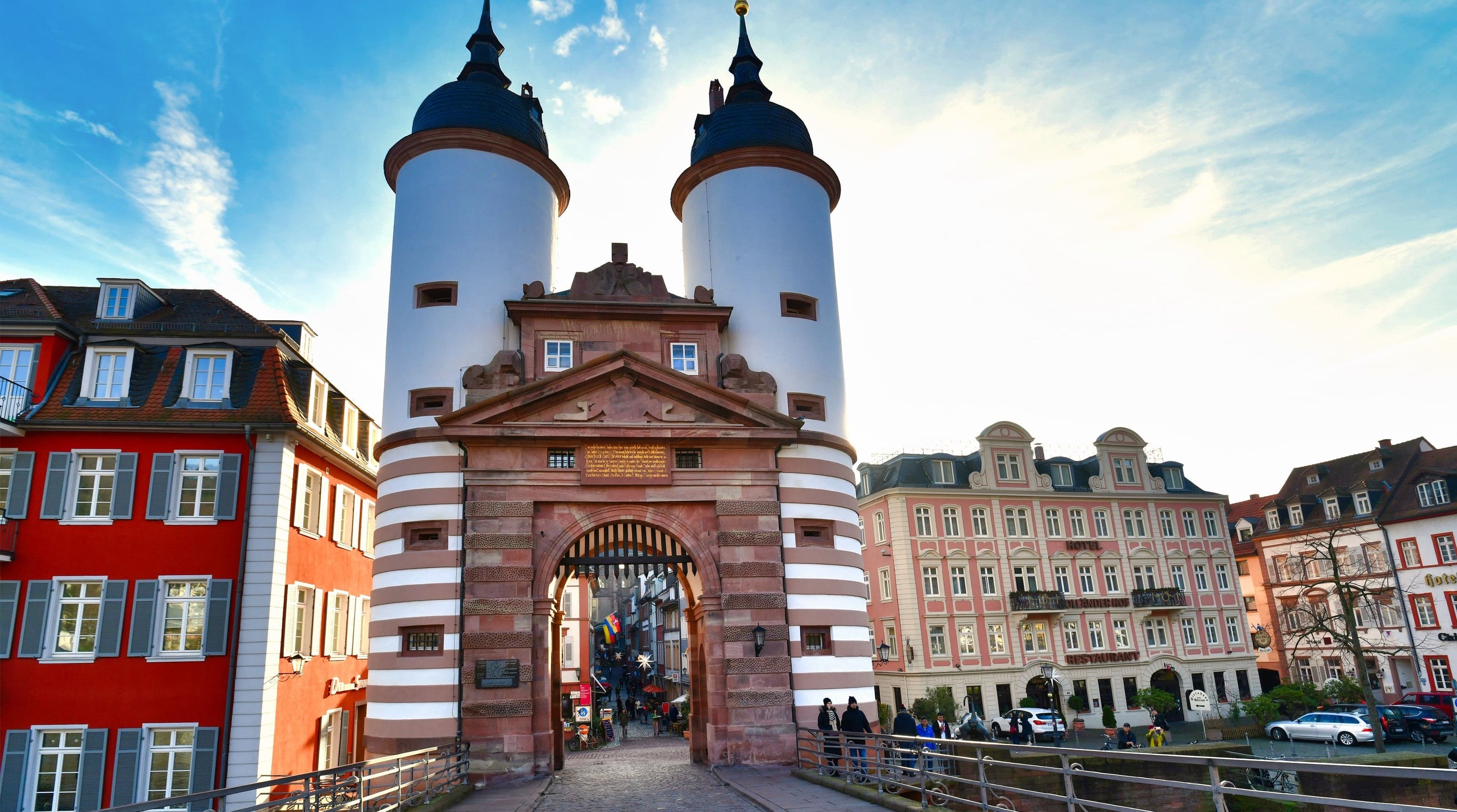 Historisches Stadttor mit zwei Türmen und Altstadthäusern bei Sonnenschein in Heidelberg, Deutschland.