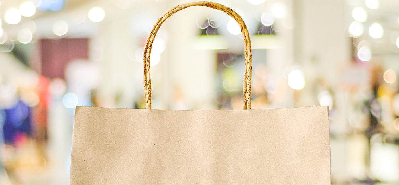 Braune Einkaufstasche aus Papier mit Griffen, nachhaltige Shopping-Bag im Einkaufszentrum mit unscharfem Hintergrund