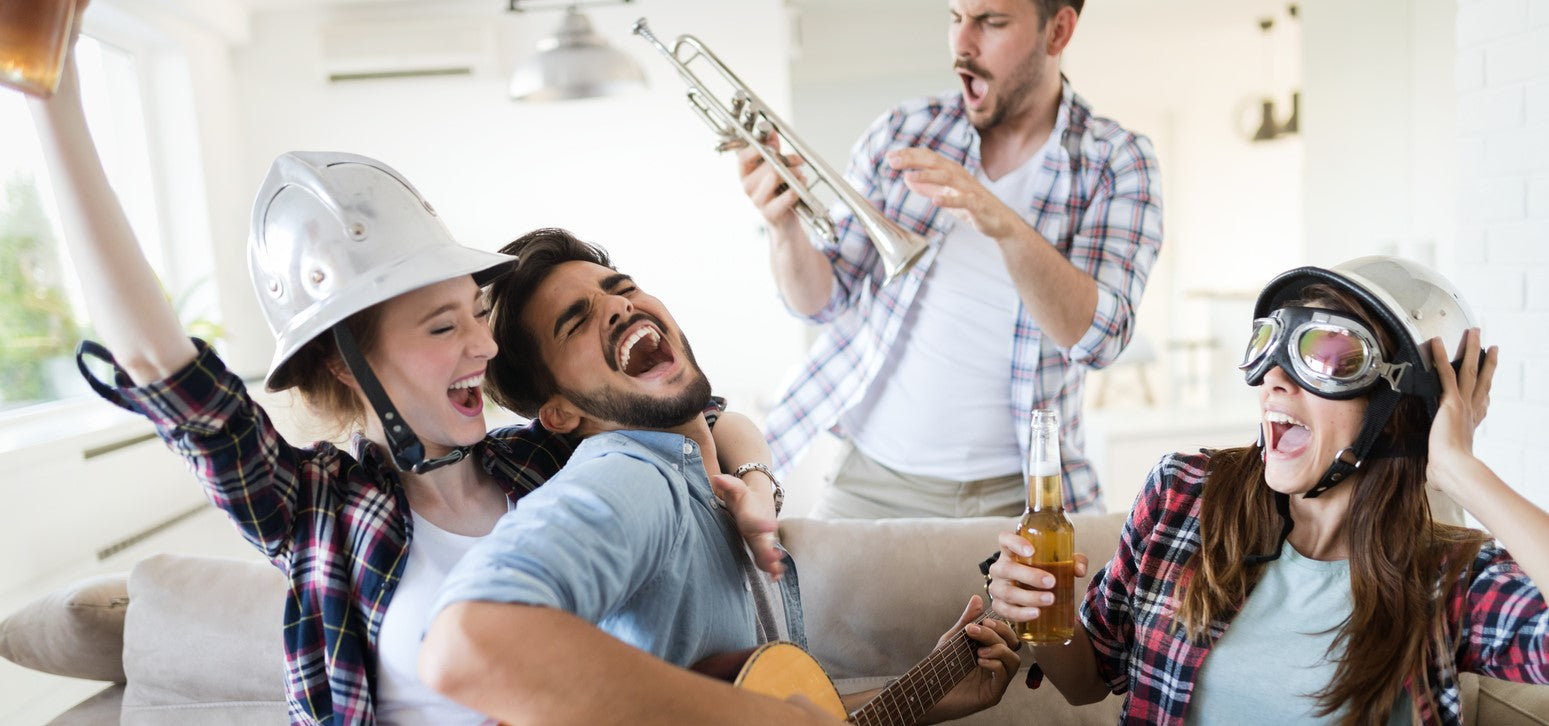 Gruppe junger Erwachsener feiert ausgelassen mit Instrumenten und Getränken – fröhliche Partyatmosphäre