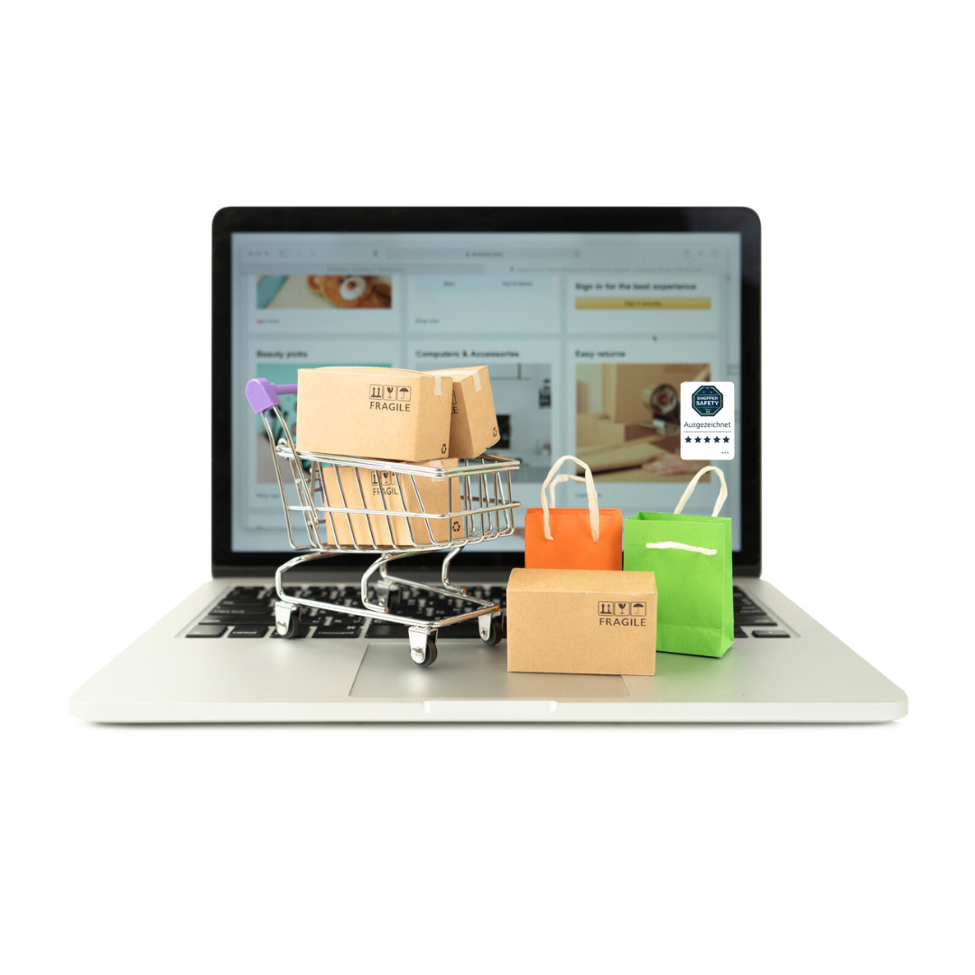 Einkaufswagen mit Paketen und Tüten auf Laptop – Symbol für sicheren Online-Shop mit Shopper Safety Gütesiegel-Safebadge